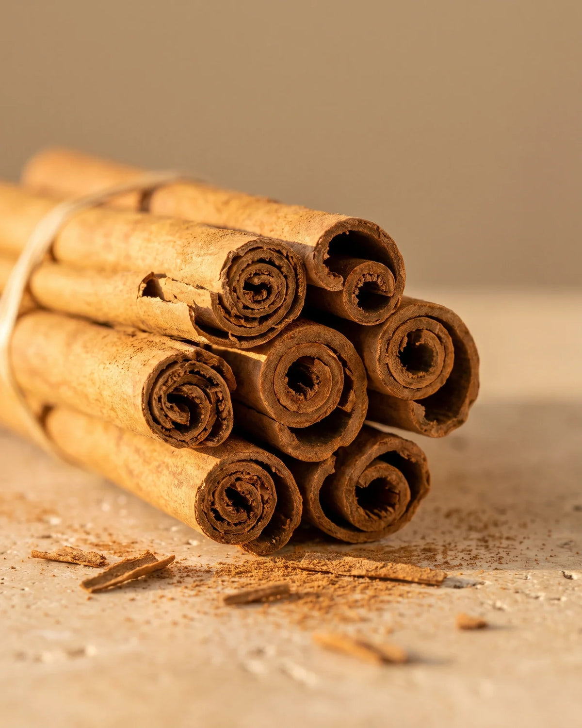Un manojo de rajas de canela con un poco de canela molida sobre travertino: el aroma dulce y especiado del aceite esencial puro de canela de Delune