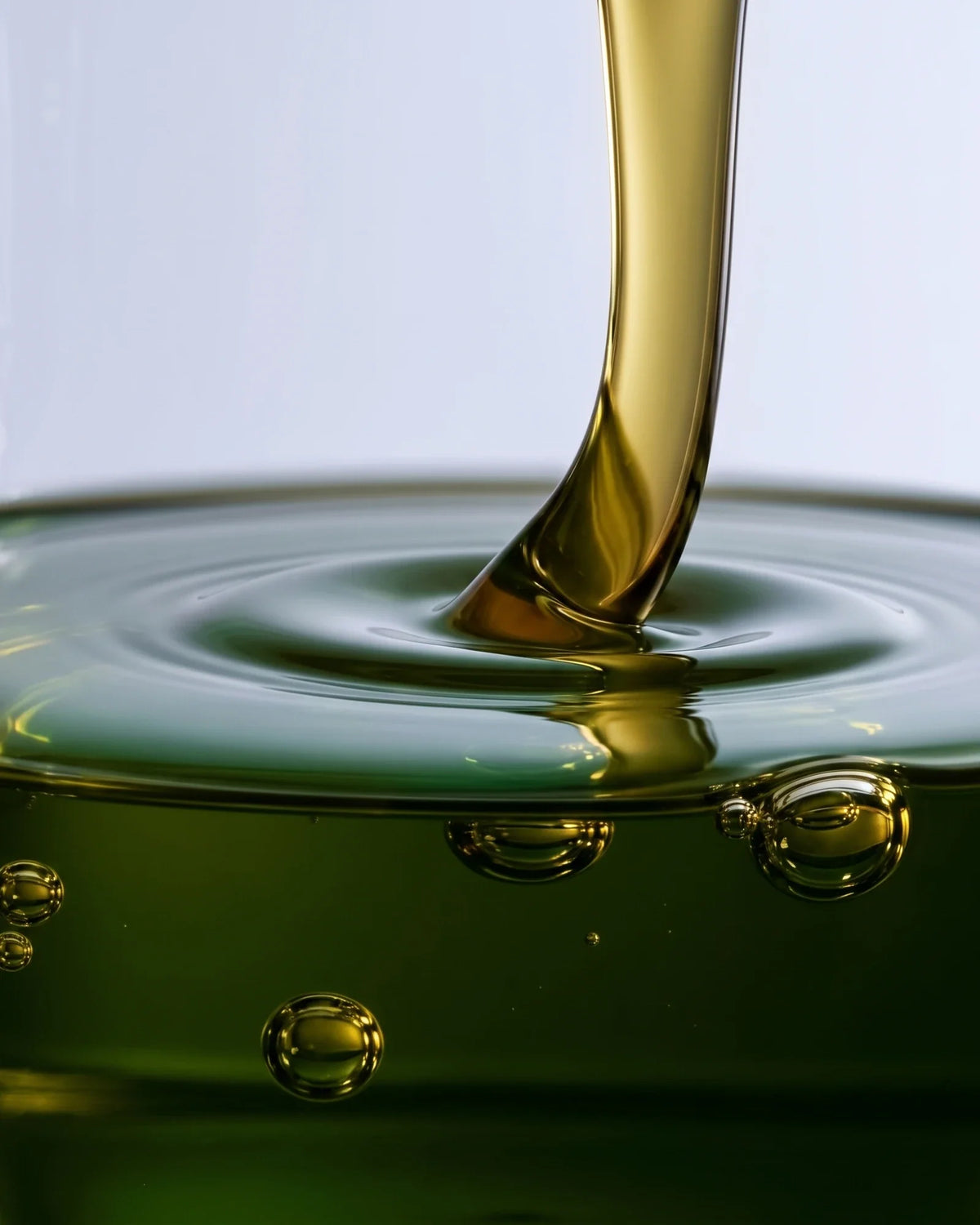 Textura del sérum Clear 49% con aceite de tamanu: aceite de tamanu verde dorado que cae sobre un charco con ondas suaves