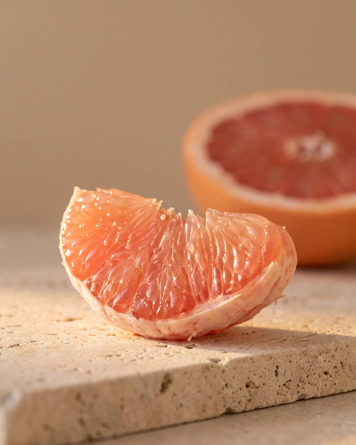 Un gajo de toronja rosada reluciente, a contraluz bajo un sol cálido: el aroma agridulce y jugoso del aceite esencial puro de toronja (rosada) de Delune