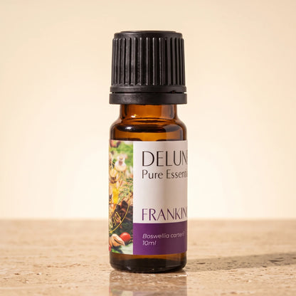 Frasco de vidrio ámbar de 10 ml del aceite esencial puro de incienso (Boswellia Carterii) de Delune sobre piedra travertino cálida