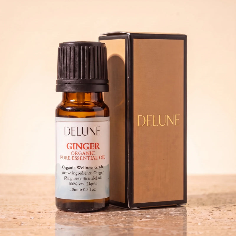 Aceite esencial de jengibre Organic Wellness Grade de Delune, frasco de vidrio ámbar de 10 ml con su caja de regalo Delune con estampado dorado, sobre piedra travertino cálida