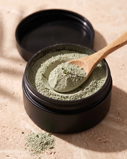Frasco abierto de arcilla con té verde de Delune con el polvo de arcilla verde salvia, suave y seco, y una cuchara de madera