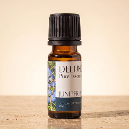 Delune Juniper Berry Pure Essential Oil, 10ml amber glass bottle on warm travertine stone