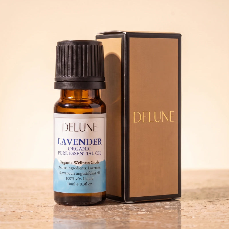 Aceite esencial de lavanda Organic Wellness Grade de Delune, frasco de vidrio ámbar de 10 ml con su caja de regalo Delune con detalles dorados, sobre piedra travertino cálida