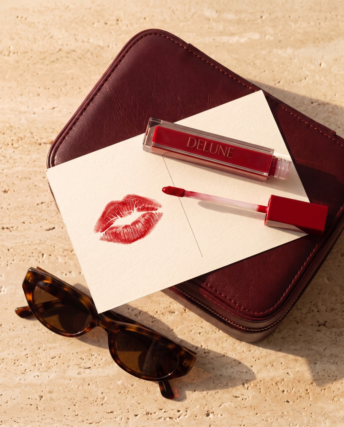 Delune LuxMatte en Jet-Set Red con un beso rojo sobre una postal