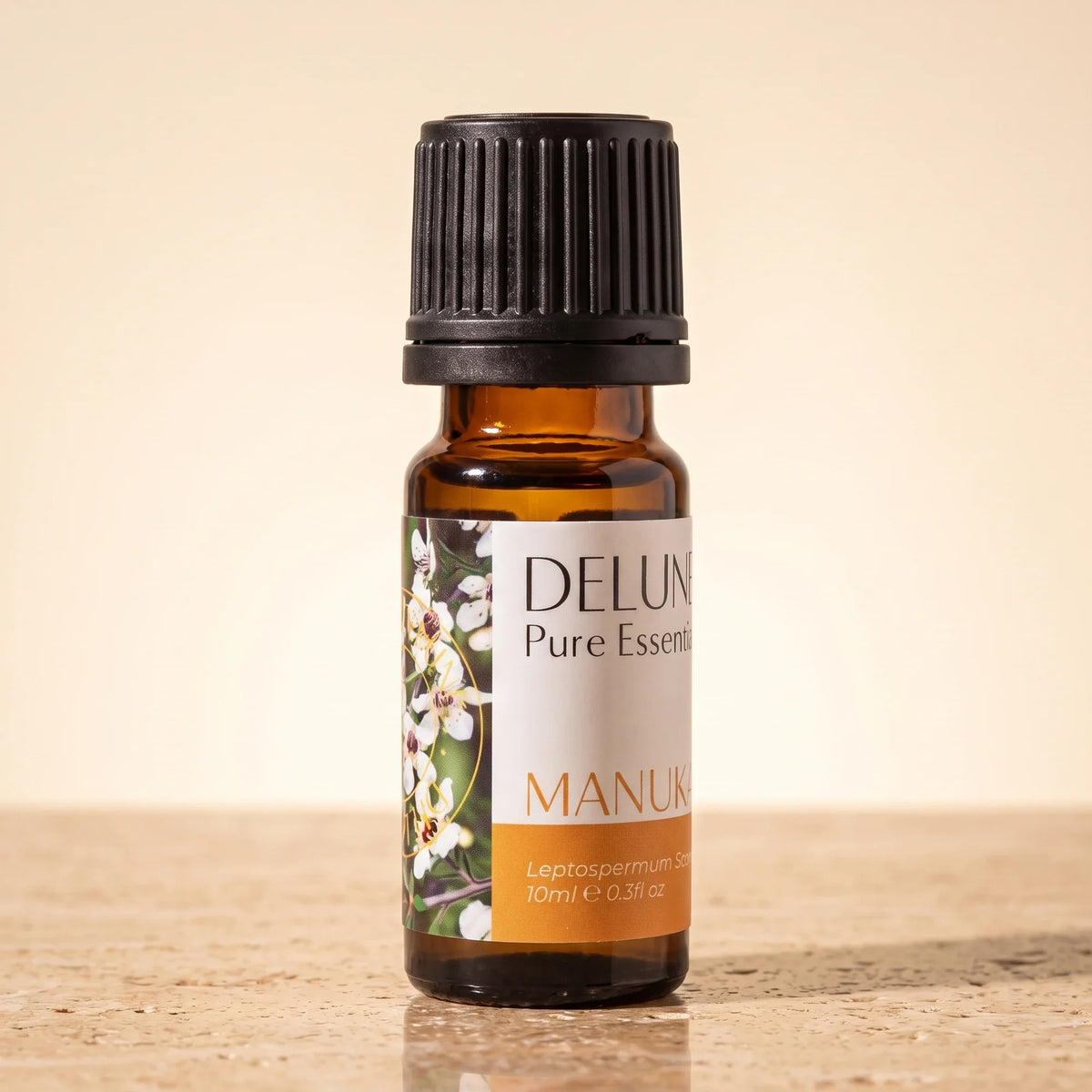 Aceite esencial puro de mānuka de Delune en frasco de vidrio ámbar de 10 ml sobre piedra travertino cálida