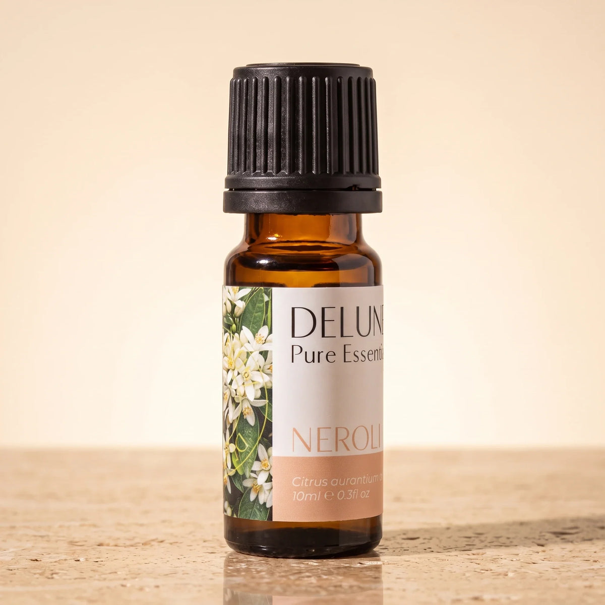 Aceite esencial puro de neroli de Delune en frasco de vidrio ámbar de 10 ml sobre piedra travertino cálida