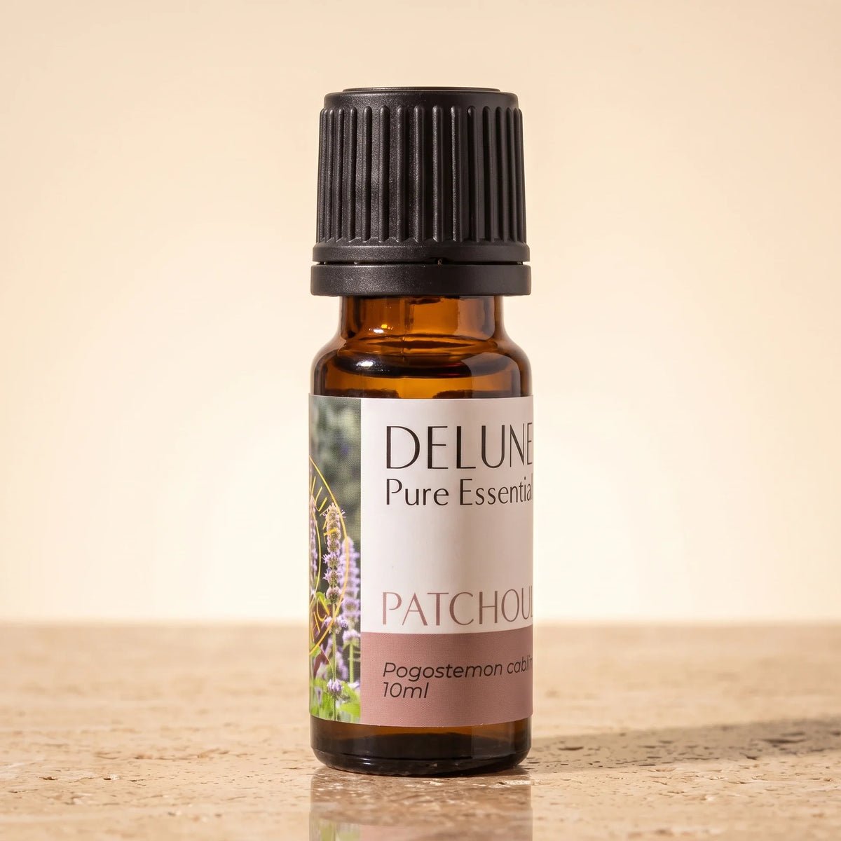Aceite esencial puro de pachulí de Delune en frasco de vidrio ámbar de 10 ml sobre piedra travertino cálida