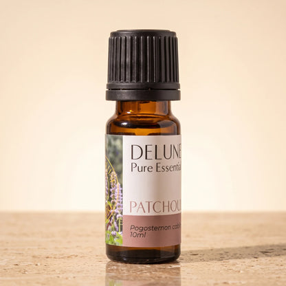 Aceite esencial puro de pachulí de Delune en frasco de vidrio ámbar de 10 ml sobre piedra travertino cálida