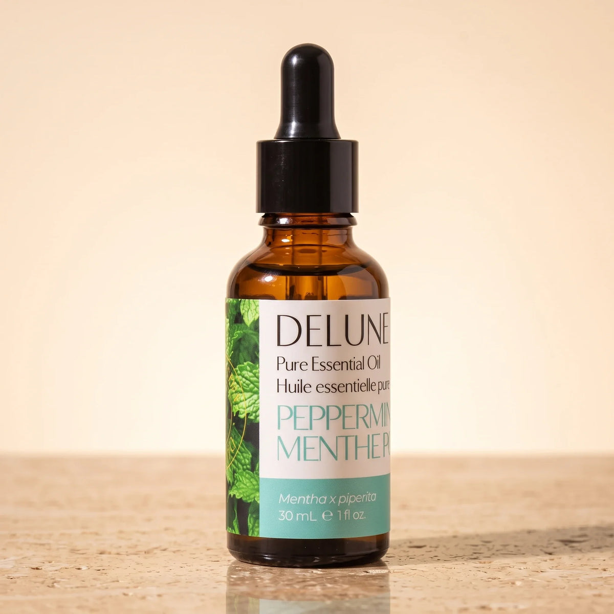 Aceite esencial puro de menta de Delune en frasco gotero de vidrio ámbar de 30 ml sobre piedra travertino cálida