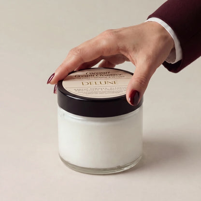 Mano sobre la tapa del limpiador en crema de coco de Delune