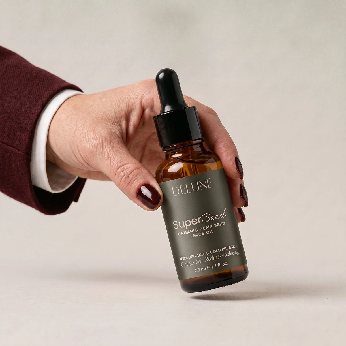 Una mano toma Super Seed, el aceite facial de semilla de cáñamo de Delune