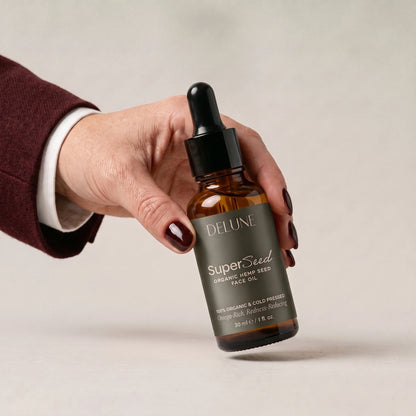 Una mano toma Super Seed, el aceite facial de semilla de cáñamo de Delune
